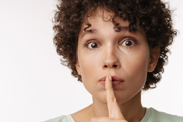 Young curly surprise woman showing silence gesture