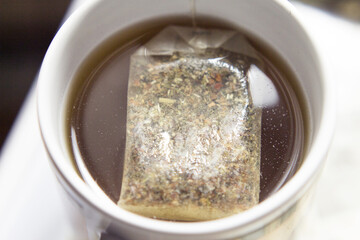 White cup with infusion and tea bag
