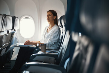 Calm woman sitting by the airplane porthole alone