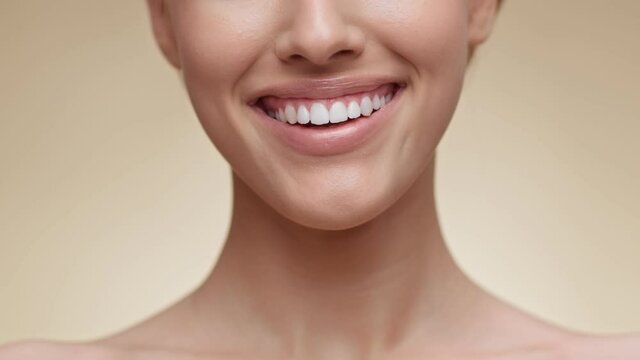 Teeth whitening. Close up shot of young unrecognizable lady widely smiling to camera, showing her perfect smile