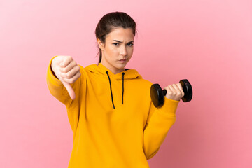 Young sport girl making weightlifting over isolated pink background showing thumb down with negative expression