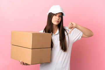 Delivery girl over isolated pink wall showing thumb down with negative expression