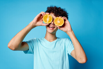 man with curly hair oranges holding fruit studio blue background