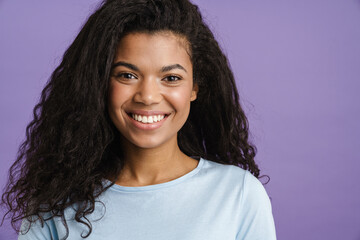 Young black woman with curly hair smiling and looking at camera