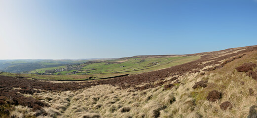 a panoramic scenic view of the village of old town in calderdale west yorkshire with surrounding pennine farms and hills with midgley moor in the foreground