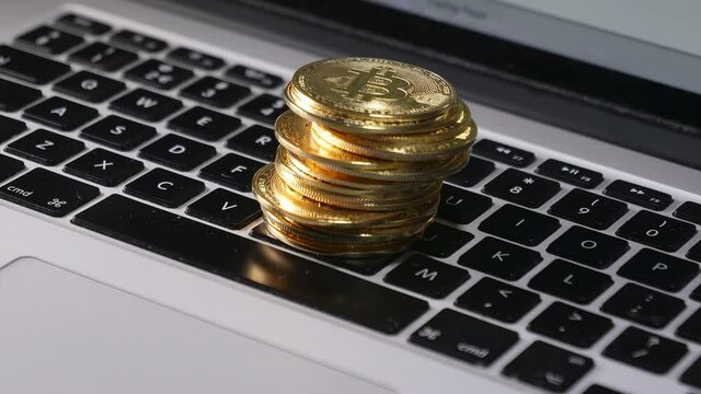 Golden bitcoins piling up on computer keyboard. Time lapse. 