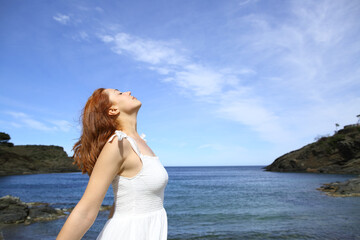 Fototapeta na wymiar Relaxed lady in white breaths fresh air on the beach