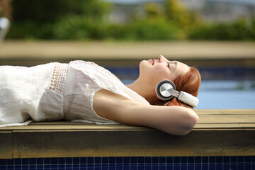 Relaxed woman listening to music with headphones in a pool