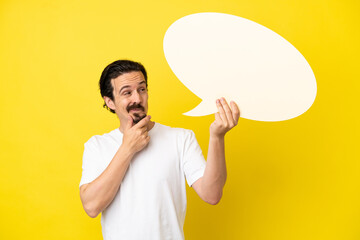 Young caucasian man isolated on yellow background holding an empty speech bubble and thinking