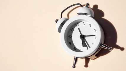 The white vintage alarm clock with shadow - flat lay.