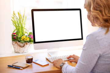 Woman working on desktop computer with empty white screen - obrazy, fototapety, plakaty