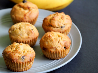 five vegan banana muffins with raisins gluten free stand on a gray plate against a black background, side view. homemade diet without lactose, eggs, gluten