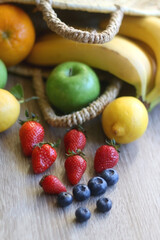 Straw bag full of various colorful fruit on wooden background. Selective focus.