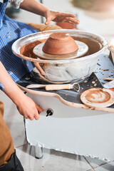 Person turning a knob of pottery wheel during work