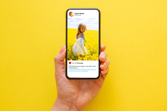 Mobile phone on yellow background with photo of woman in yellow meadow on the screen