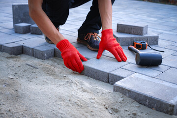 The master in yellow gloves lays paving stones