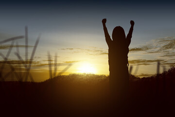 Fototapeta premium Silhouette of a little girl with a backpack with happy expression with sunset background