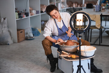 Fototapeta premium Potter tilting head and looking to camera during pottery creation