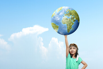 Asian cute girl in an aviator cap holding earth with a blue sky background