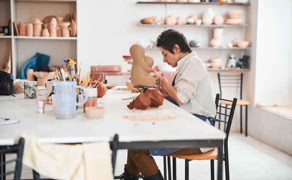 Master potter carving leg of statuette from clay