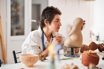 Woman checking out her pottery work for flaws