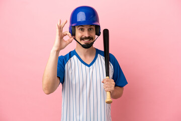 Young caucasian man playing baseball isolated on pink background showing ok sign with fingers