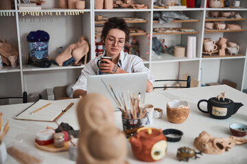 Pottery maker surfing the internet while having a drink - Powered by Adobe