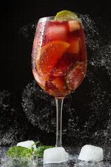 Fresh summer sangria splashing on black background