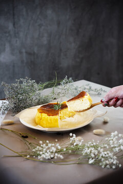 Cheese cake with a hand holding wooden spoon and taking a piece of cake off.