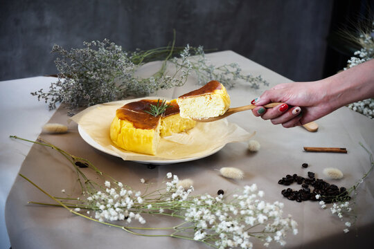 Cheese cake with a hand holding wooden spoon and taking a piece of cake off.