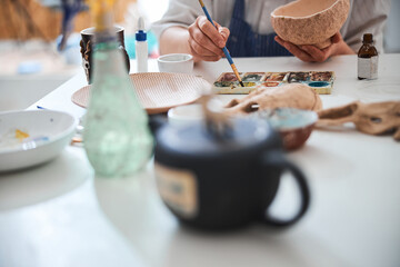 Adult reaching for paint with brush during pottery painting