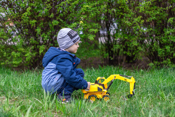 little boy playing with a toy car on a green lawn