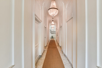 Classic design of hallway with carpet and white doorway under crystal chandeliers and with spiral...