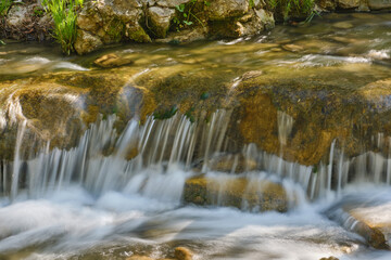 Fototapeta na wymiar Stream in the forest. Brook with pure mountain water. Smoky mountain waterfall. Shallow depth of field