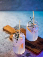 Alcoholic cocktail with gin and rosemary. A chilled glass . Color lighting, stone table