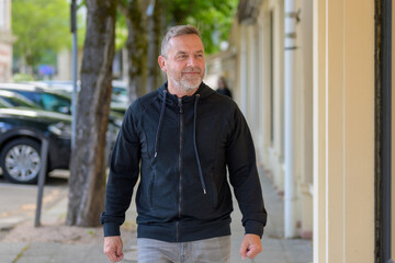 Middle-aged man in leisurewear walking down an urban street