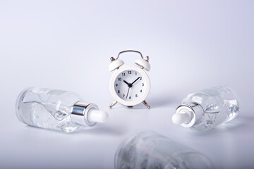 Bottles of face serum are lying around on a white table around the clock.