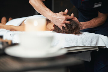 Unrecognized female on massage table getting relax procedure on head in spa salon