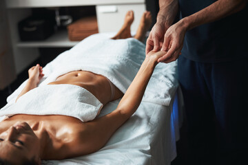 Beautiful charming woman under the towel lying on massage table receiving new massage technique in wellness center