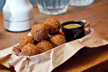 Cheese balls on a pile close up. Round cheese with sauce in a plate on a wooden table.