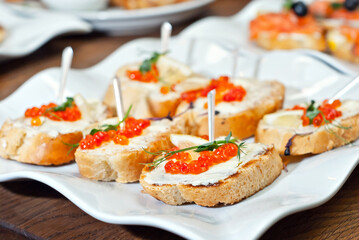 Sandwich with caviar and seafood on a white plate.