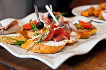 Sandwiches with meat on a white plate. Sandwiches with ham and olives close up.