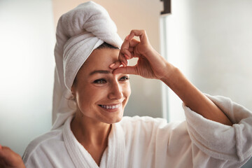 Beautiful charming young woman with towel on head looking away while relaxing in spa salon