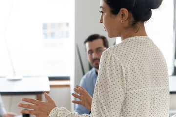 Close up back view Indian businesswoman mentor coach leading briefing, training employees workers...