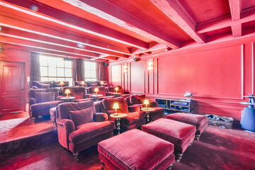 Pink colored luxury room with red velvet armchairs in cinema hall of mansion house