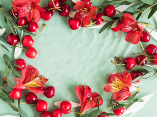 Cherry frame with red flowers and petals in water on natural green background