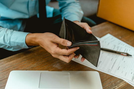Man hands open empty purse looking for money.
