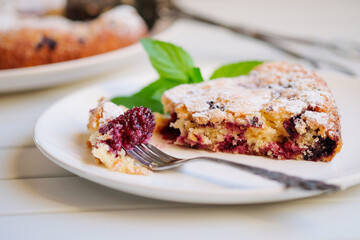 Piece of homemade simple pie with fresh red raspberries and black mulberry on a light background. Summer berry dessert. close up