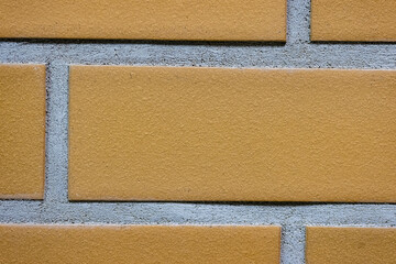 Fototapeta premium Close-up texture of a yellow brick wall with a gray seam