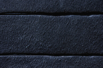 Close-up texture of a black decorative scratched brick with a gap
